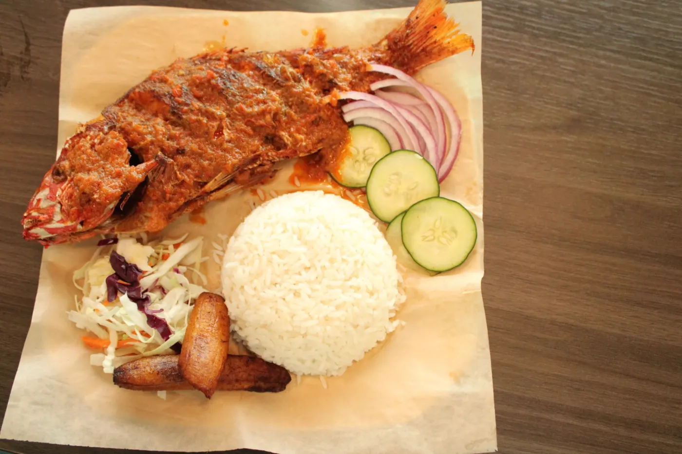 Whole fish served with rice, onion, cucumber, and plantain at M&M African Kitchen